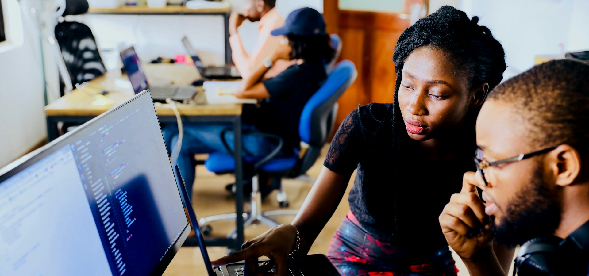 A consultant mentoring a colleague through a technical task at a workstation