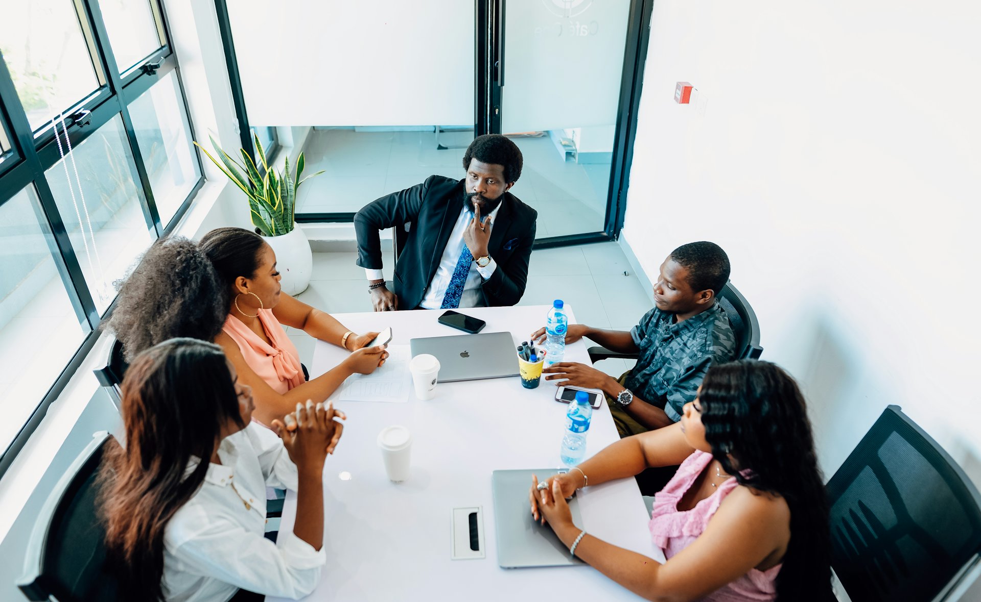 A leader chairing a meeting with a team of professionals in a bright boardroom